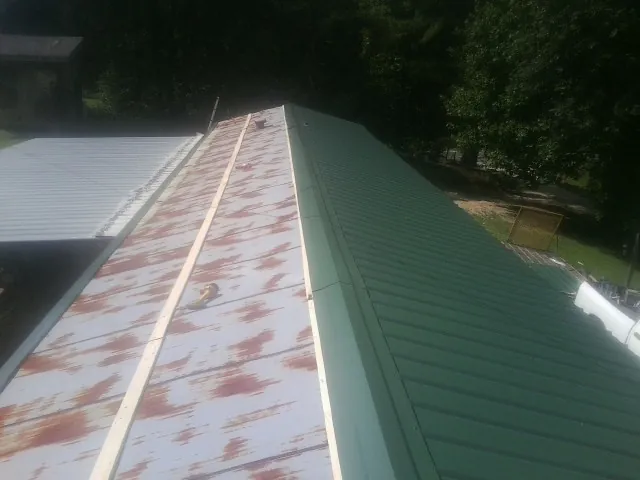 Old rusted panels beside newly installed green metal roofing — Wind Damage Roof Repair by Roofing Brothers in Irrigon