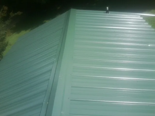New green metal panels meeting at the ridge of a roof — Flat Roof Repair work by our crew in Irrigon