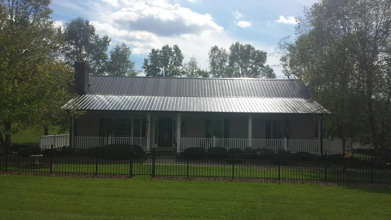 Gray metal roof on a brick ranch with a full width front porch — Gutter Guard Installation work by our crew in Irrigon