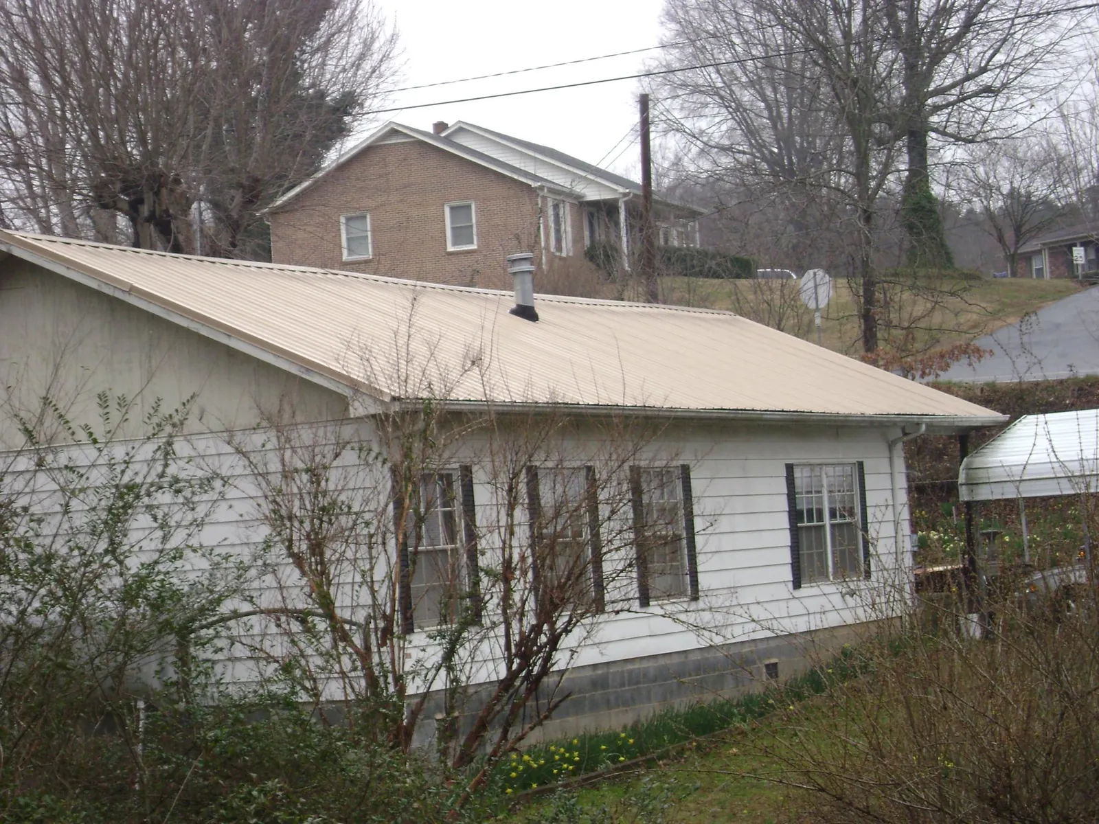 Tan metal roof on a white sided house set into a hillside — Commercial Roofing by Roofing Brothers in Irrigon