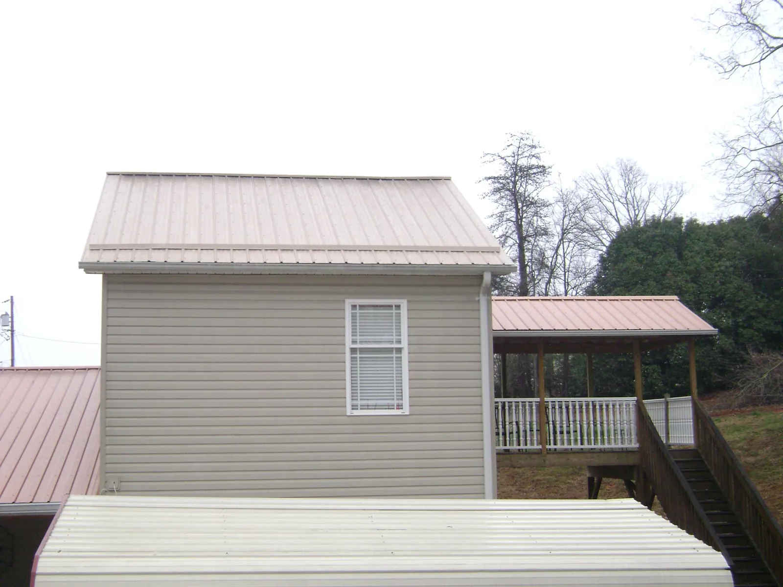 Tan metal roofs on a two story addition and attached porch, from a Roof Replacement job in Irrigon
