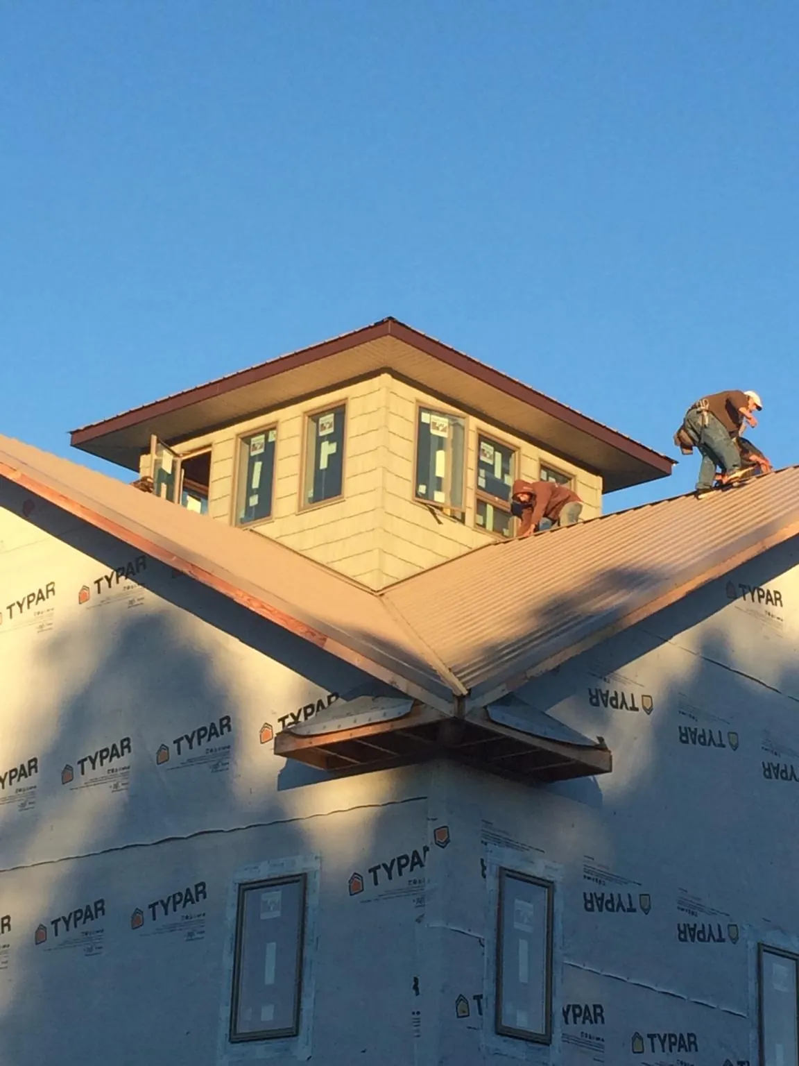 Roofers working around a rooftop cupola on a new metal roof at sunset — Roof Waterproofing in Irrigon by Roofing Brothers